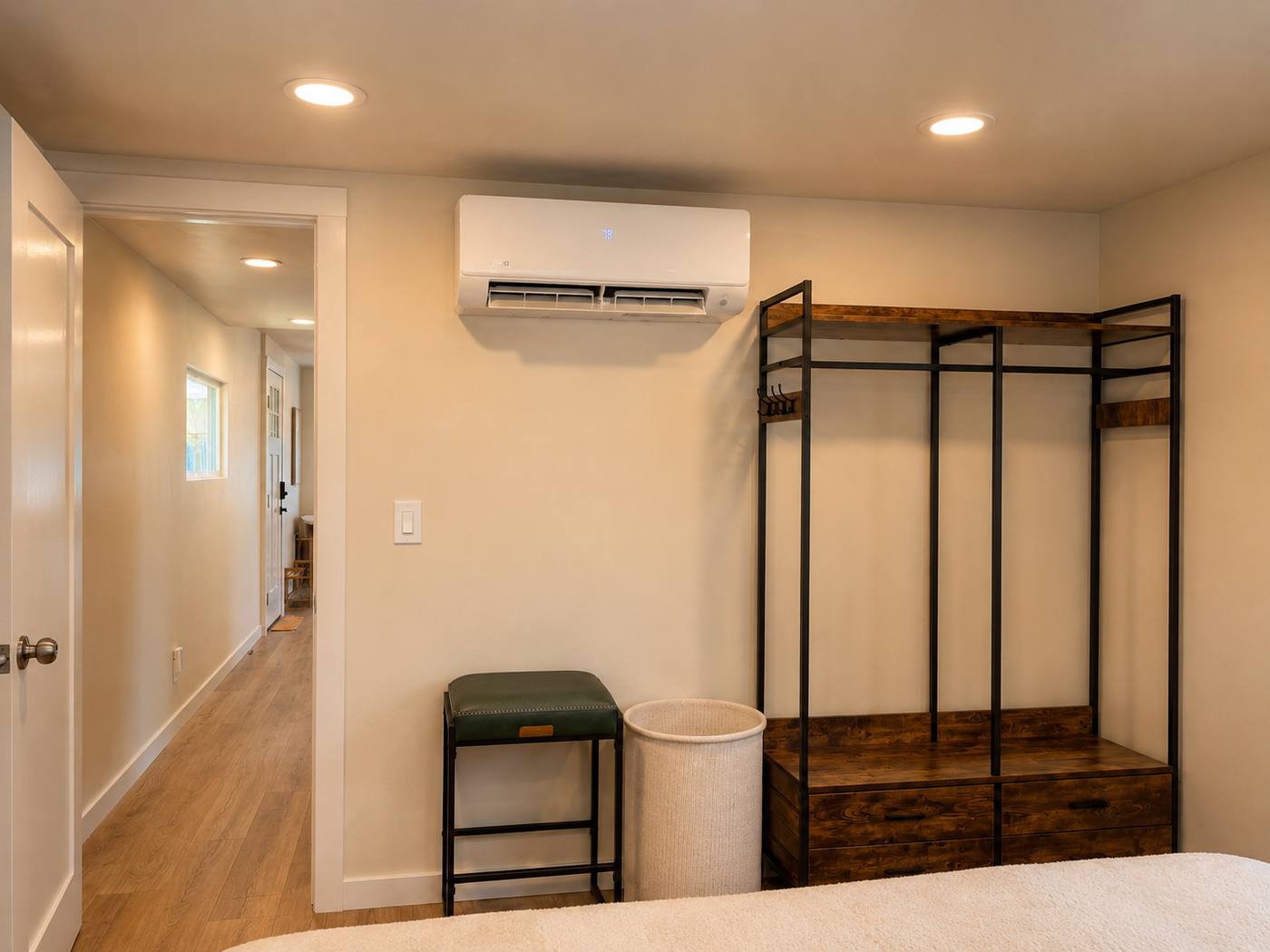 Bedroom storage rack with hanging rail and drawers, wall-mounted mini-split, hallway beyond