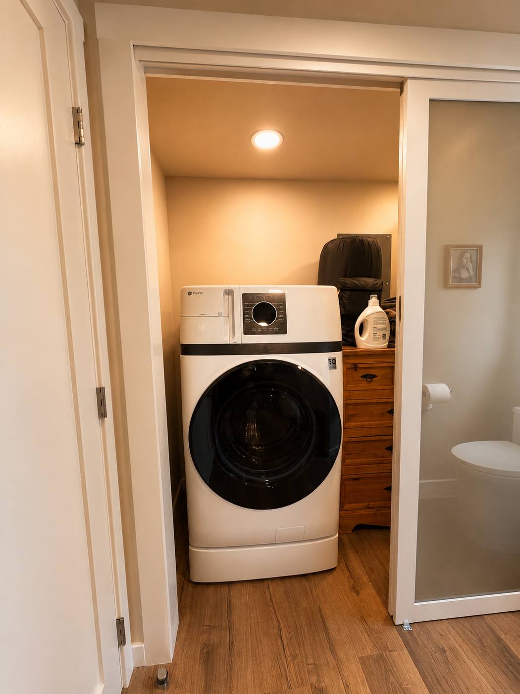 Full-size washer and dryer in a lit utility closet off the hallway