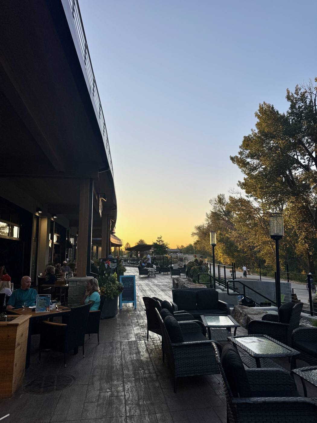 A Boardwalk restaurant terrace at dusk, tables out along the river walk