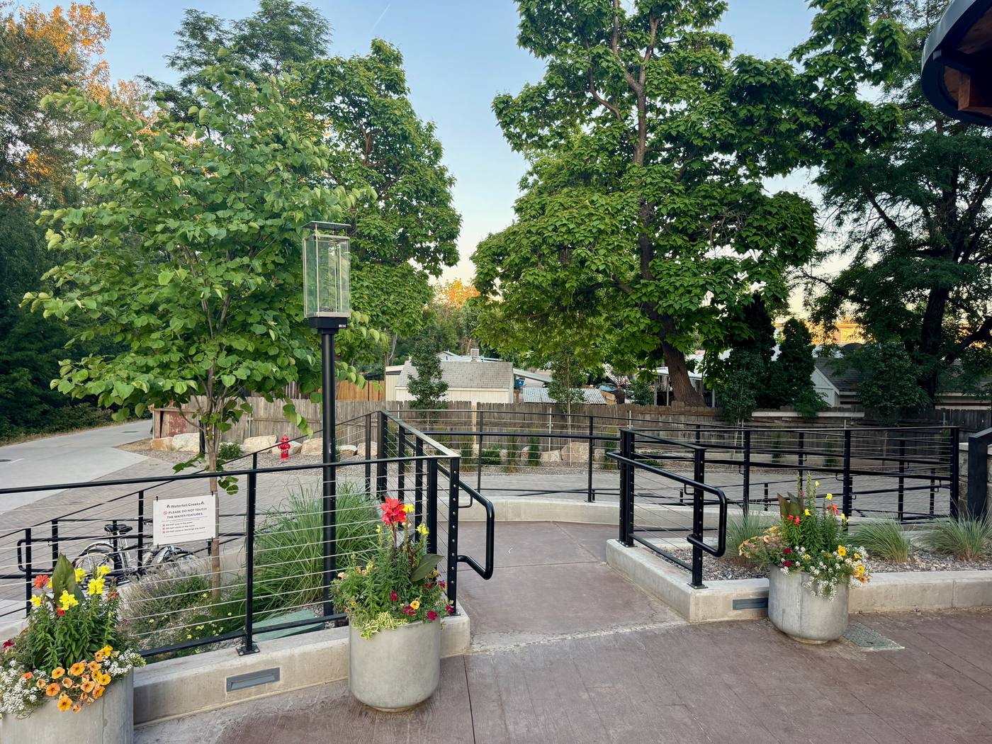 The Boardwalk plaza with planters and cable railings, the Greenbelt running past