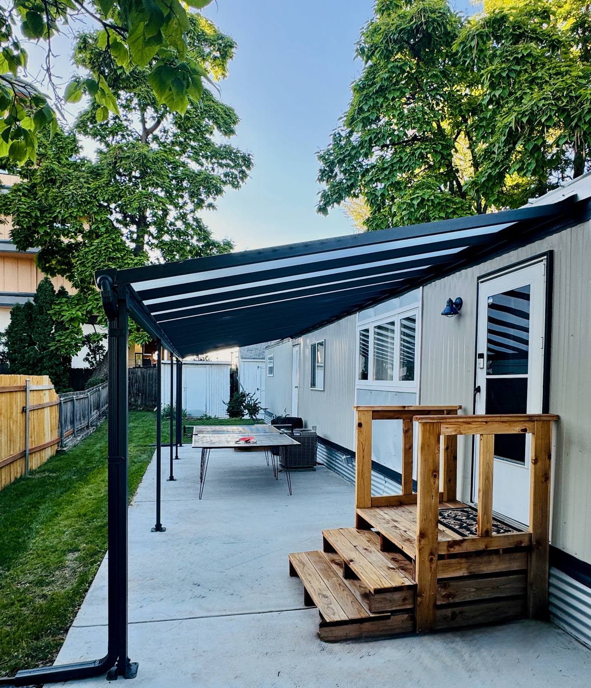 Covered patio running the length of the house, with a ping-pong table and cedar steps down to the lawn