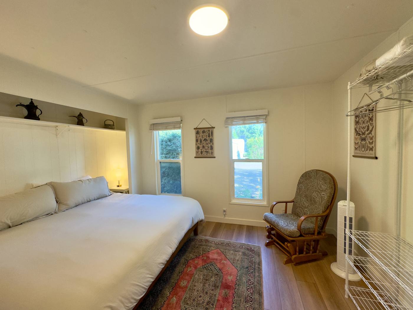 Second bedroom with a king bed, patterned rug, rocking chair and a clothes rail